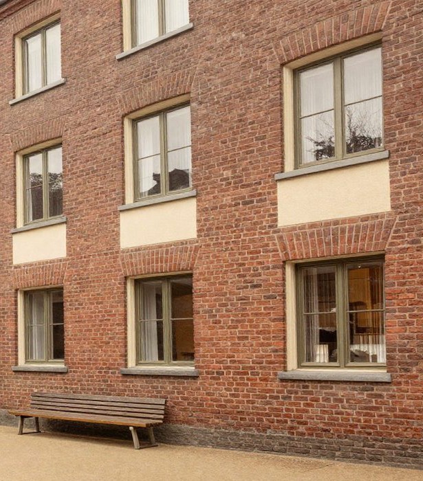 Symbolbild, KI-generiert: dreigeschossiges Backsteinhaus mit Haustür und Bank